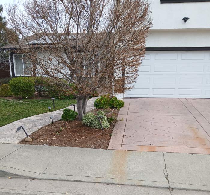 Custom stamped concrete patio driveway with a decorative natural stone texture and border design, providing durable curb appeal and a low-maintenance paving solution for homeowners