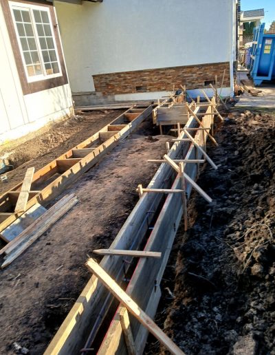 Long view of wooden formwork and steel rebar reinforcement installed for a residential concrete foundation footing.