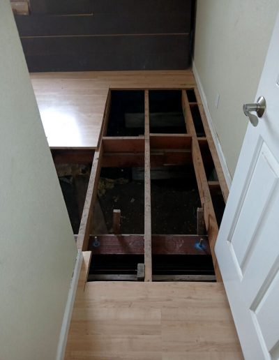 Interior view of a home showing existing floor removed to expose the crawl space and framing for a foundation tie-in.