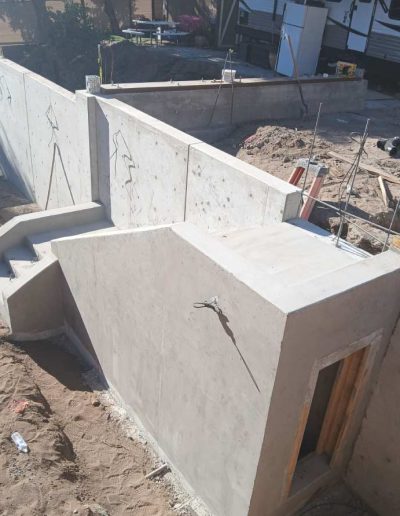 This image showcases a complex, finished concrete retaining wall with integrated steps and a customized entry, demonstrating our expertise in complex structural concrete work on sloping terrain. Our work ensures maximum stability and functional access, adding value to the property.