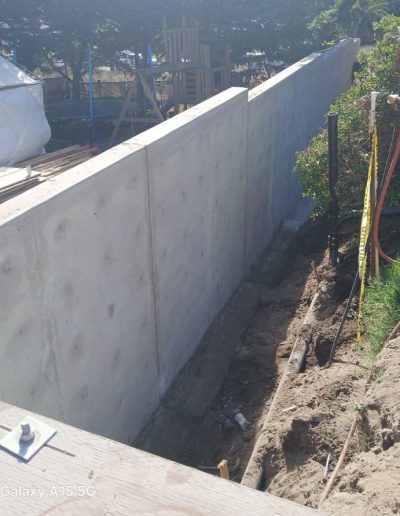Finished reinforced concrete retaining wall with integrated steps and entrance, built for soil retention and custom property access.